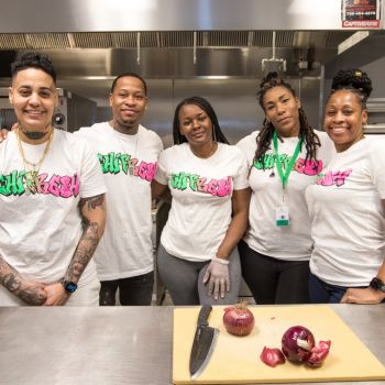 A group of five people wearing chi fresh white t shirts in a kitchen with onions on the table.