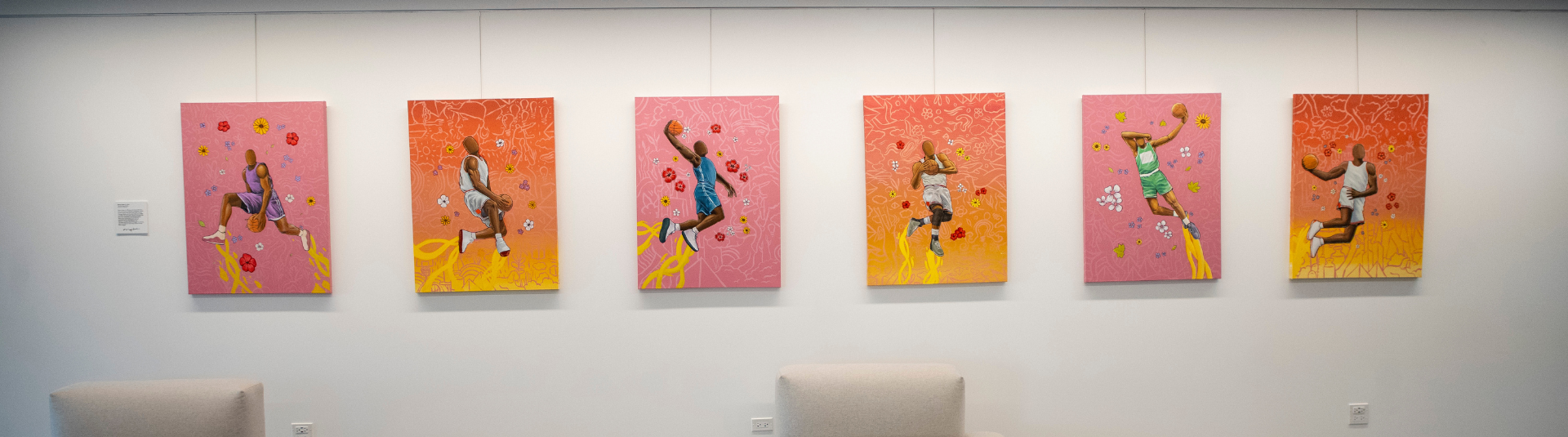 A wall with painted basketball players in midair with a ball in their hands. Each photo has a colorful orange and red backdrop.
