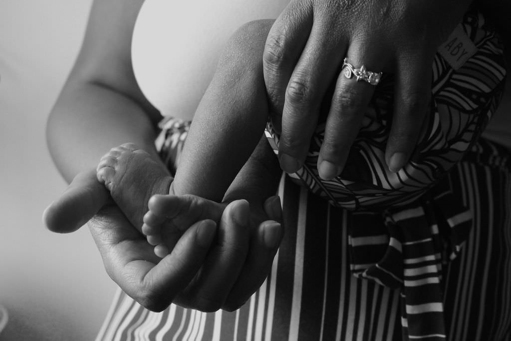 A close up photo on adult hands holding a new born baby.