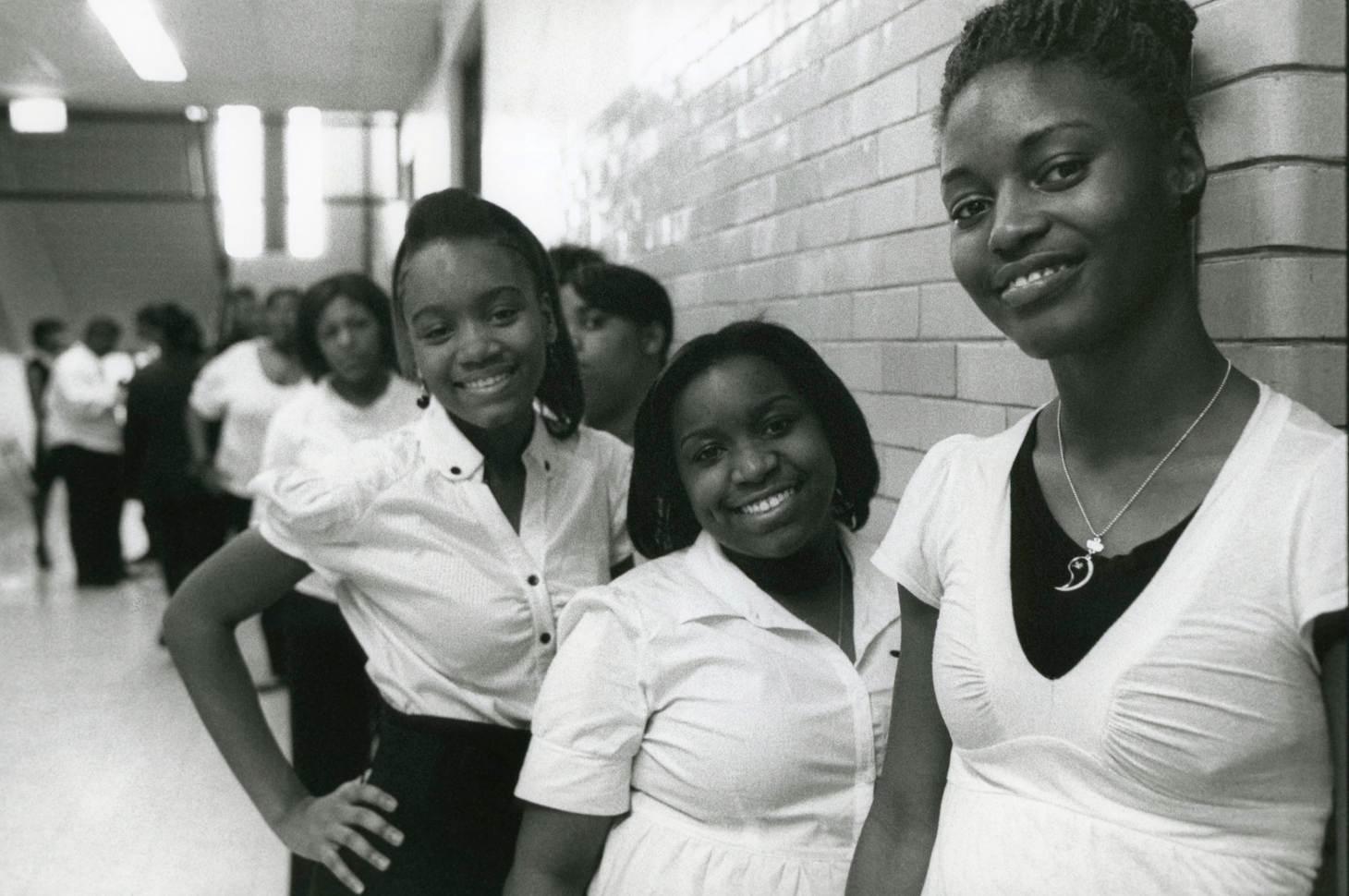A black and white photo of smiling Black high school students in a hallway