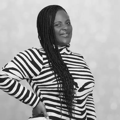 Woman with long hair wearing a black and white stripped long sleeve shirt, smiling against a plain white background.